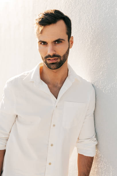 istock Confident young ethnic guy leaning on wall and looking at camera 1475885356