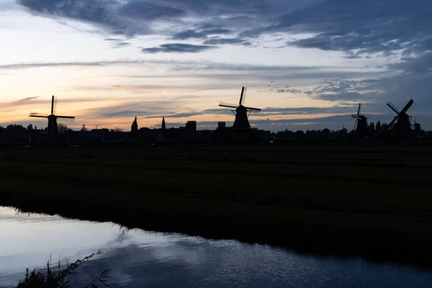 Landscape of dark silhouettes of traditional Dutch windmills during an evening sunset in Zaanse Schans Netherlands