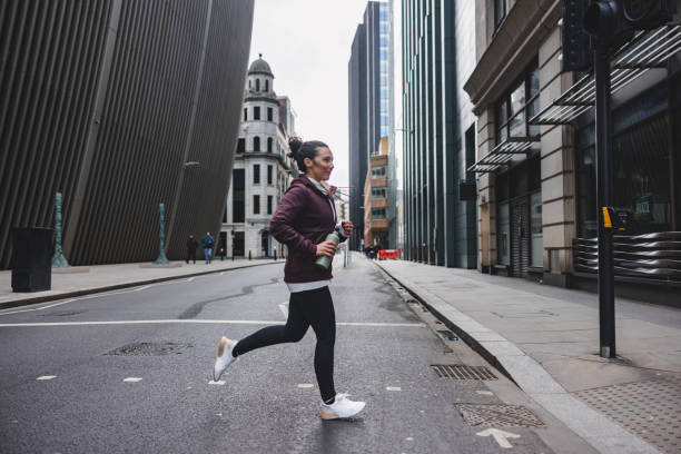マラソンの準備のためにロンドンの街を走り回る水筒を持つアクティブな成人白人女性 - marathon running london england competition ストックフォトと画像