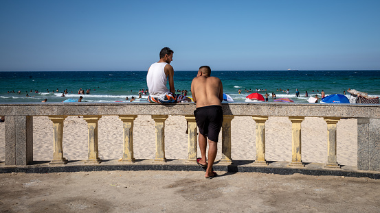 Two men chat next to Bou Jaafar Beach in Sousse, Tunisia.