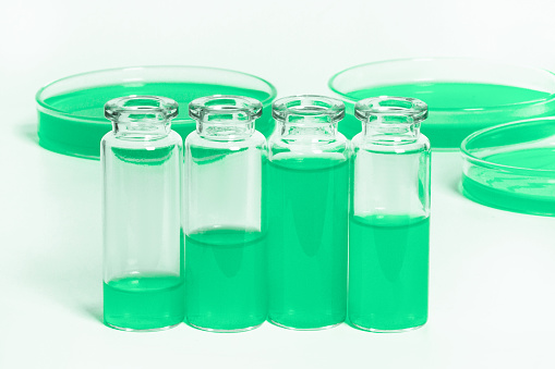 a set of flasks, jars for the laboratory with a green liquid. Against the background of laboratory glassware. Petri dishes, flasks, test tubes. On a white, light background.