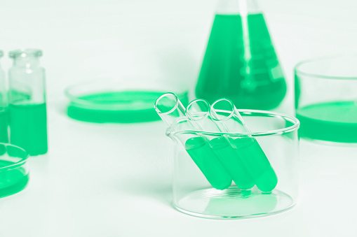 Test tubes for the laboratory with green liquid.On the background of laboratory glassware. Petri dishes, flasks, test tubes. On a white, light background.