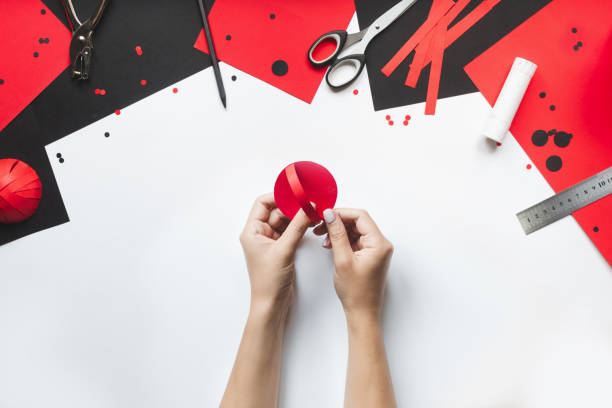istock How to make paper red and black ladybug toy with children at home. Step by step instructions. Hands making DIY summer project. Top view. Step 7. Glue folded parts of strip to circle 1475911117