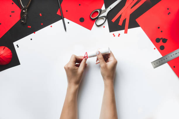 istock How to make paper red and black ladybug toy with children at home. Step by step instructions. Hands making DIY summer project. Top view. Step 6. Apply glue to folded parts of strip 1475911166