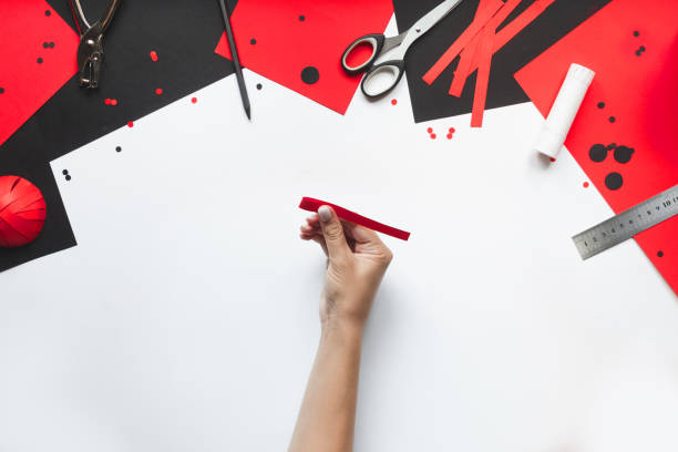 istock How to make paper red and black ladybug toy with children at home. Step by step instructions. Hands making DIY summer project. Top view. Step 5. Fold all strips on 2 cm on each side 1475911229