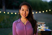 Portrait of an asian woman looking at the camera. Chinese female at restaurant with a nice smile is standing on the terrace in front of a table.