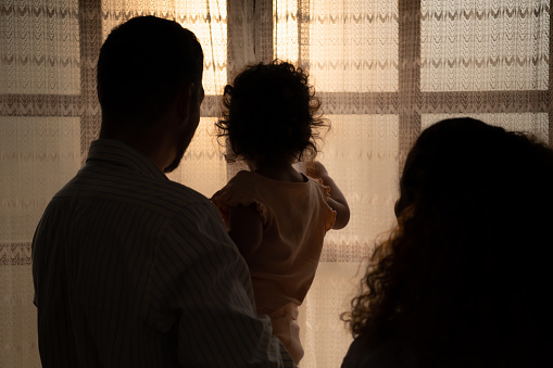 Parents and children enjoy the morning sunlight shining through the bedroom window in the house.