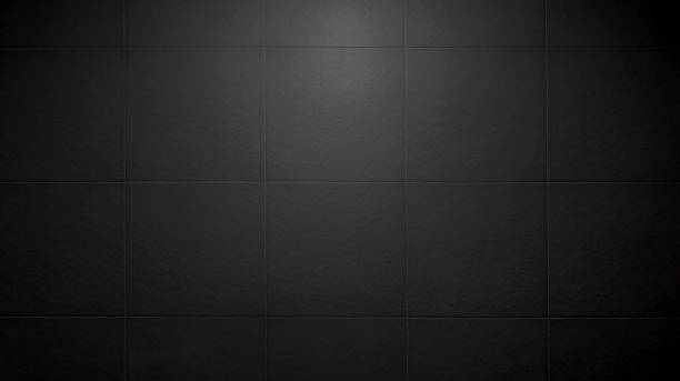 slate tile ceramic for industrial interior decoration style. close up dark black square tile pattern with light from above used as background. large rustic bathroom tile pattern.