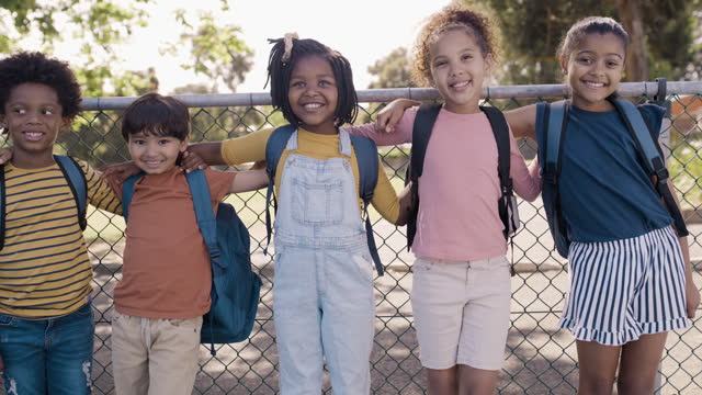 Kids, education and diversity with a group of students standing outside together on a playground during break. Children, learning or school with girl and boy pupils bonding outdoor during recess
