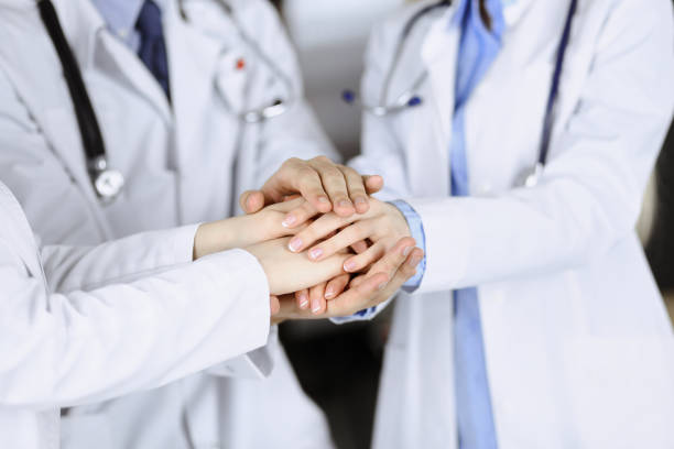 istock Group of modern doctors joining hands as a circle and ready to help patients. Teamwork in medicine during Coronavirus pandemic. Covid 2019 1475927251