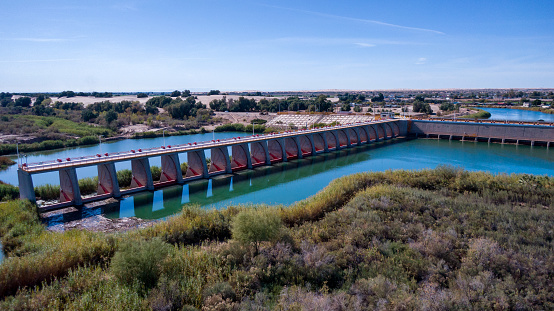 The Colorado Diversion Dam in Yuma, Arizona, marks the start of one of the most extensive irrigation systems in the United States. The dam, constructed in the early 1900s, diverts water from the Colorado River to the fields and farms of the surrounding area. The river flows through a series of canals and channels, carrying life-giving water to the crops that sustain the region's economy. The surrounding landscape is a patchwork of green fields and orchards, a testament to the ingenuity and hard work of the farmers who have made the desert bloom. The Colorado Diversion Dam is a symbol of the power of water to transform and sustain, a vital resource in a harsh and unforgiving environment.