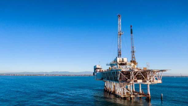 chiudi la piattaforma di perforazione di petrolio e gas off-shore con navi da carico in distanza al crepuscolo vicino a long beach / los angeles, california al crepuscolo in una mattina limpida - oil rig sea oil storm foto e immagini stock