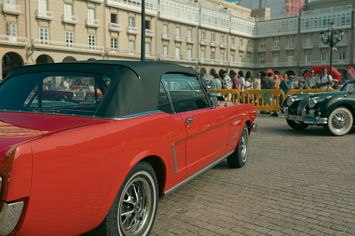 August 12, 2022, Spain A Coruna: he iconic Ford Mustang Cabriolet in red captures the essence of classic car design. This vintage automobile is a representation of a bygone era, full of history and nostalgia. The cabriolet is a classic example of a restored, luxury vehicle that boasts shiny chrome details, a beautiful front end, and elegant styling. A true collector's item, this retro machine is a perfect symbol of urban lifestyle, with its glossy red exterior that catches the eye and its classic design. Whether you're an auto enthusiast or just love the beauty of vintage vehicles, the Ford Mustang Cabriolet is the perfect example of an old-fashioned, expensive, and famous car that you'll love to have in your collection. Enjoy the wonderful memories of the past as you travel back in time with this elegant and amazing car, a true masterpiece of the auto industry.