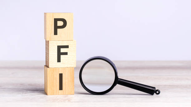 istock PFI - Private Finance Initiative - text wooden cube blocks and magnifying glass on table. strategy, marketing, and content concept 1475934580