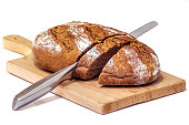 Rustic Wholegrain Brown Bread Loaf on Wooden Cutting Board Sliced With Stainless Steel Bread Knife Set on Neutral White Background
