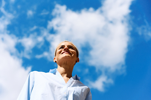 Low angle portrait of a businesswoman looking away outdoors in a sunny day