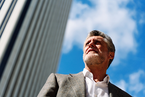 Low angle portrait of a businessman with elegant clothes standing outside a financial building