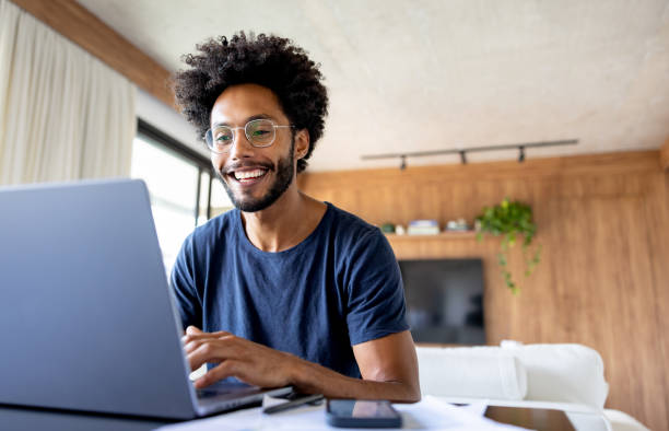 istock Happy man working at home on his laptop and smiling 1475954350