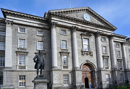 Dublin, Ireland - March 2023: Main entrance to the campus of Trinity College of Dublin with statue of philosopher Edmund Burke