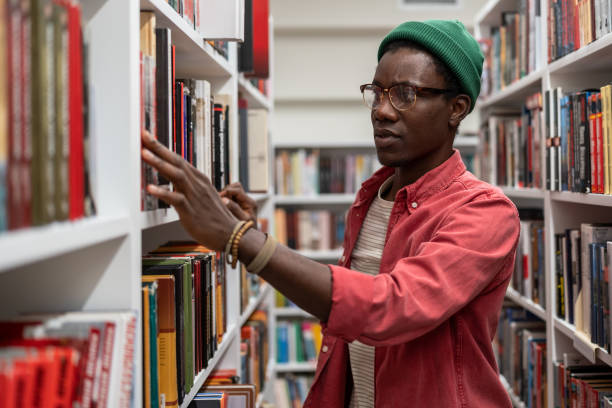 istock African guy University student standing between bookshelves in library 1475957162