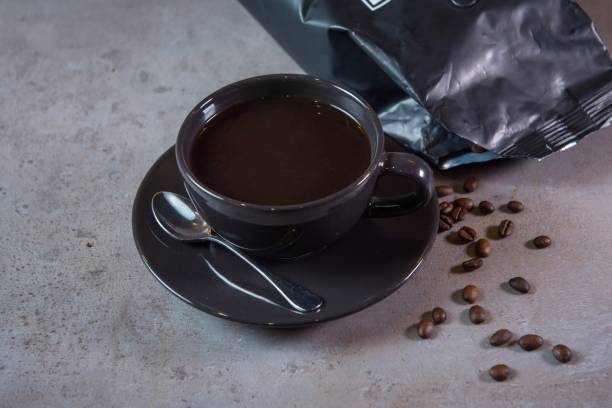 istock Hot Americano serving in coffee cup with spoon and beans side view on grey background 1475969434