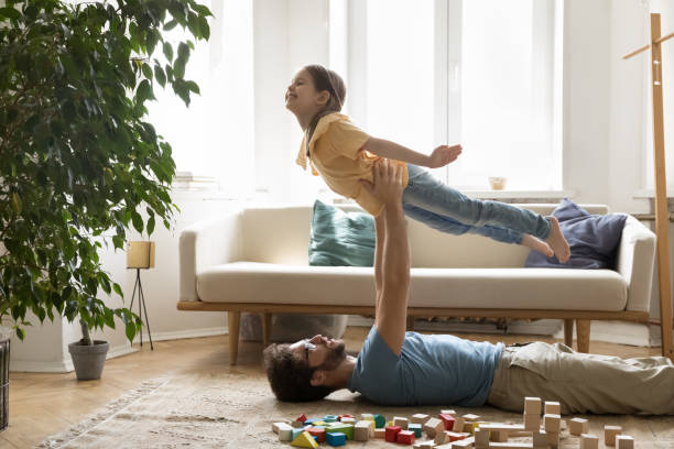 istock Joyful excited sportive kid girl playing airplane with dads support 1475970001