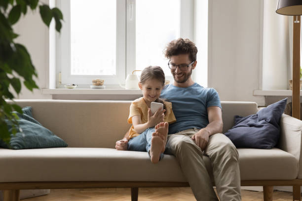 istock Happy dad hugging curious daughter girl using online learning app 1475970085