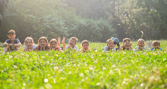 A group of children on a meadow, lying down and enjoying themselves.