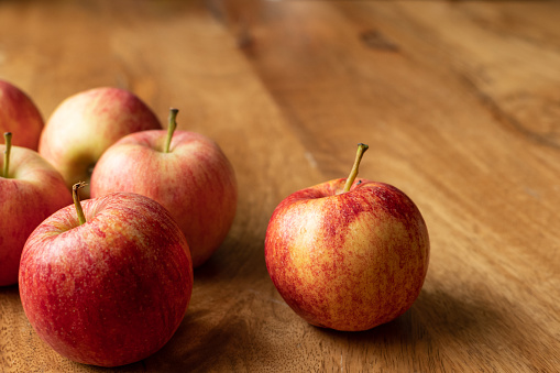Red apples on a wooden table. A symbol of good health and future happiness associated with Aphrodite, goddess of love. The Christian symbol of sin and forbidden fruit, fertility in Norse mythology.