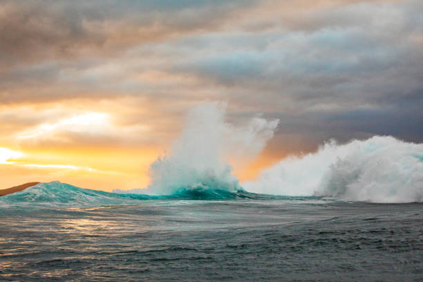 Wave exploding in golden light against sunrise in the ocean on a stormy morning, photographed in Western Australia.