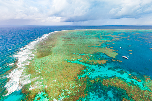 Aerial view of the Great Barrier Reef on clear sunny day with coral head atolls and natural reef patterns and boats. Queensland, Australia.