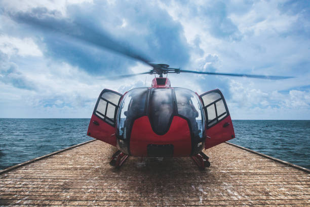 Red helicopter getting ready to take off on floating ocean pontoon landing platform