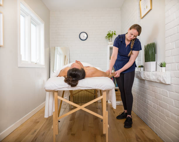 istock Female massage therapist treating female patient 1475998894