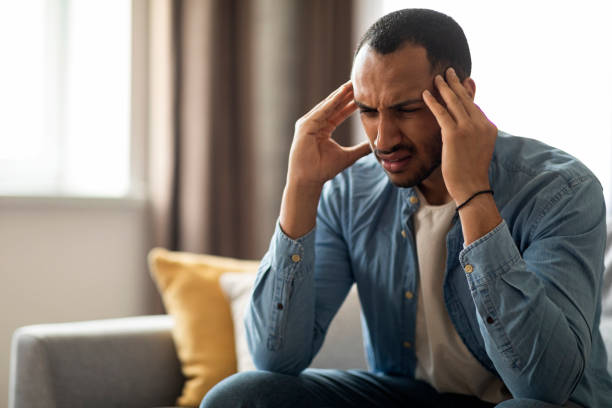 istock Stressed African American Man Suffering Headache While Sitting On Couch At Home 1476001420