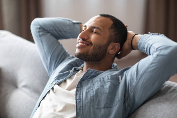 istock Domestic Comfort. Relaxed Young Black Man Leaning Back On Couch At Home 1476001443