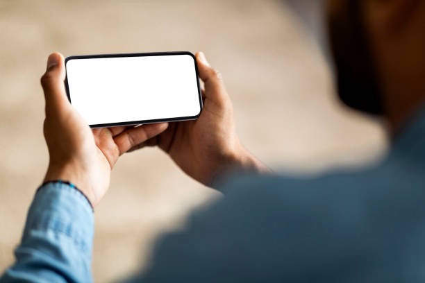 istock Unrecognizable African American Man Holding Smartphone With Blank White Screen At Home 1476001732