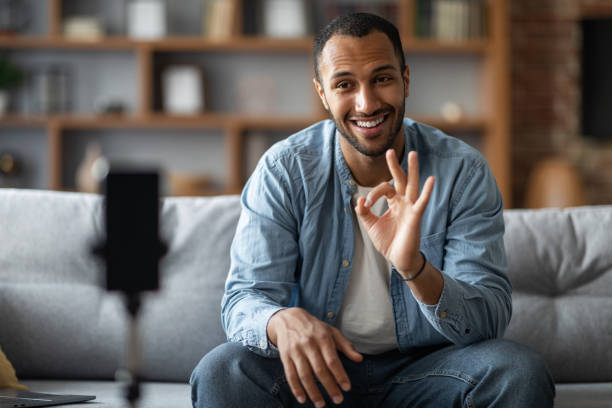 istock Smiling Black Man Using Smartphone On Tripod For Recording Video At Home 1476001747