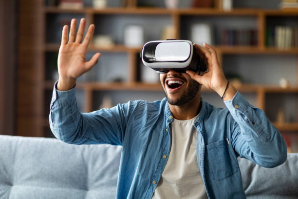 istock Excited Black Man Using VR Glasses While Relaxing On Couch At Home 1476002034