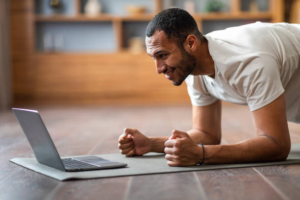 istock Domestic Trainings. Sporty Black Guy Doing Plank Exercise In Front Of Laptop 1476002036