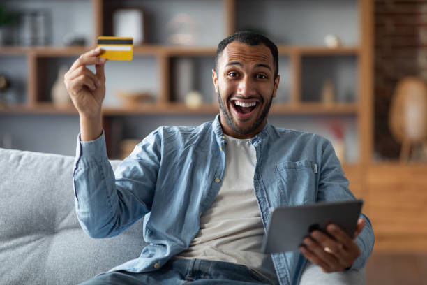 Online Shopping. Overjoyed Black Guy Using Digital Tablet And Credit Card