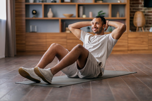 Abs Workout. Sporty Young African American Man Doing Crunches At Home, Smiling Handsome African American Guy Exercising On Fitness Mat In Living Room Interior, Enjoying Domestic Trainings