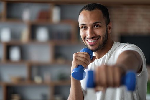 Domestic Sports. Portrait Of Handsome African American Man Training With Dumbbells Indoors, Closeup Shot Of Happy Sporty Black Guy Exercising At Home, Enjoying Healthy Lifestyle, Copy Space