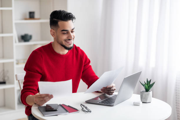 istock Smiling Arab Male Freelancer Working With Papers At Home Office 1476002733