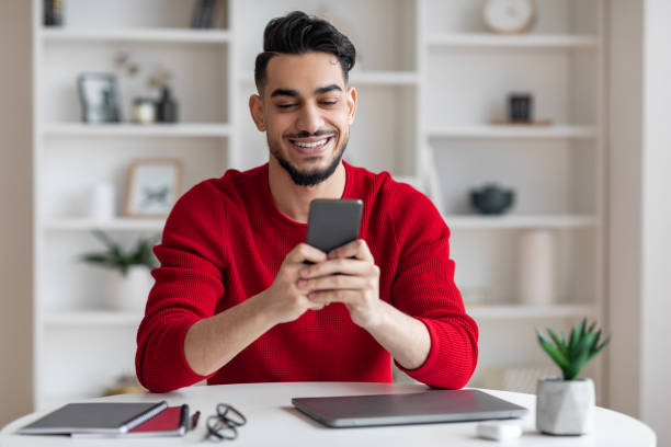 istock Arab Male Freelancer Using Smartphone While Sitting At Desk In Home Office 1476002743