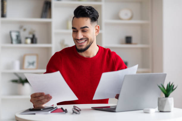 istock Cheerful young middle eastern man manager with beard works with documents at workplace with computer 1476002766