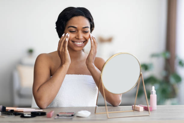 istock Attractive young black woman applying make up and smiling 1476002780