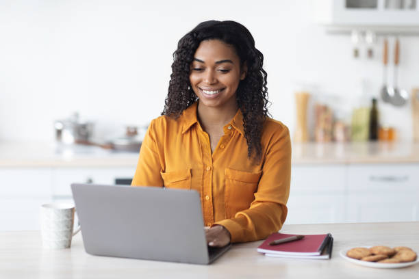 istock Happy black woman working from home, typing on notebook 1476003795