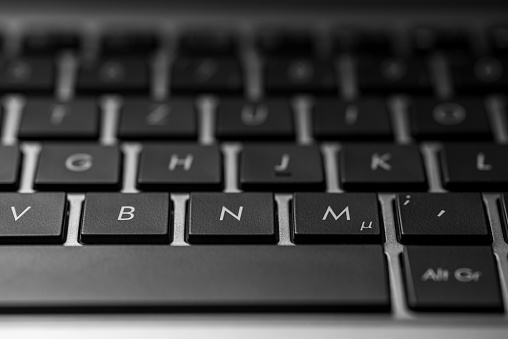closeup of a laptop keyboard with black keys and a silver case
