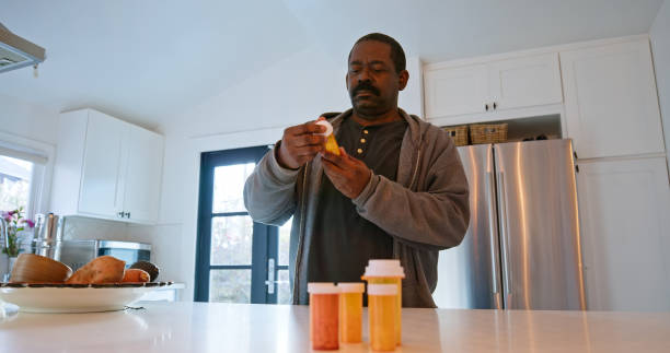 hombre afroamericano mirando el frasco de píldoras - opening bottle pill bottle pill fotografías e imágenes de stock