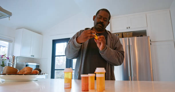 istock African American Man Inspects Pill Bottle Inside the Kitchen 1476004309